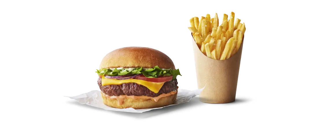 Burger avec salade, fromage et sauce, accompagné de frites dorées dans un cornet.